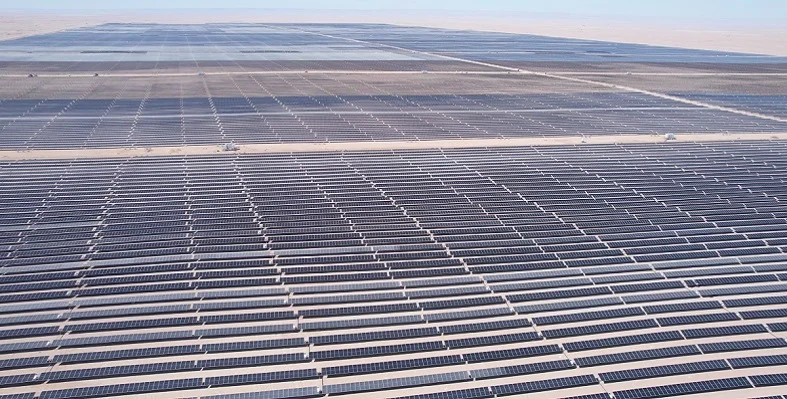 A wide shot of a large solar plant with thousands of panels in the desert.