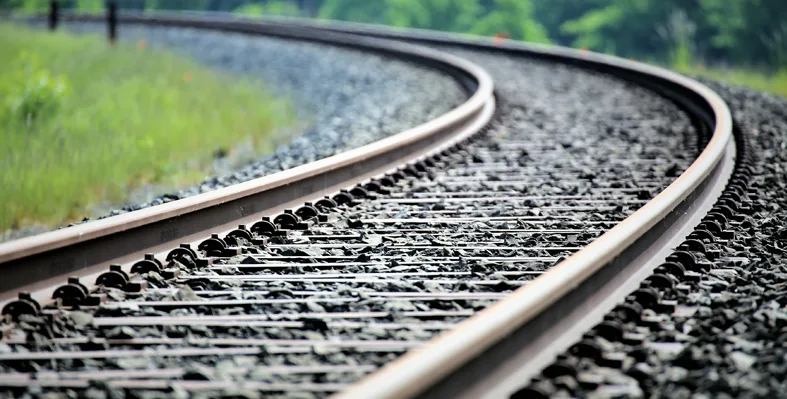 A curved railway track stretching into the distance, surrounded by greenery.