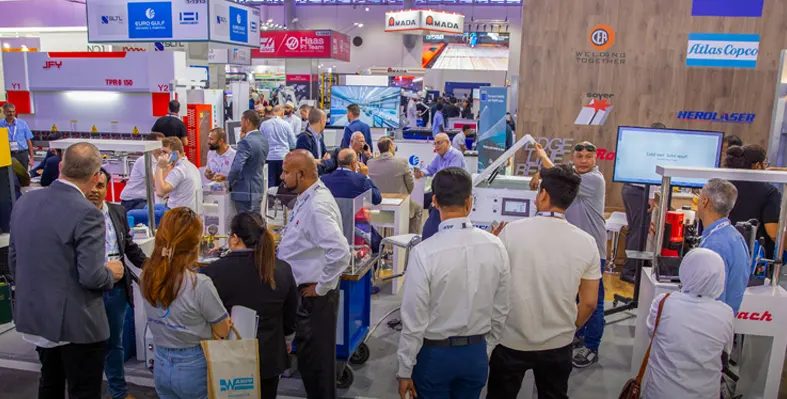 A busy trade show booth with attendees exploring industrial equipment on display.