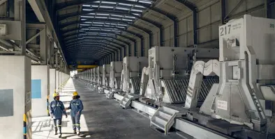 Two_workers_in_PPE_walking_through_a_facility.