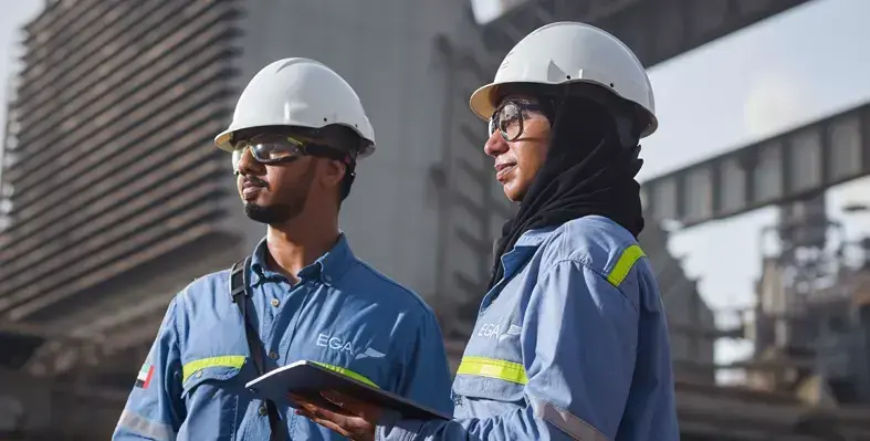 Two engineers in safety gear, including hard hats and protective glasses